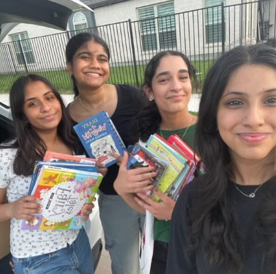 Image of the SFS team holding books collected for the Cook Children's Book Drive